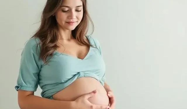 Mujer embarazada con vestido azul claro, acariciando su vientre y sonriendo con ternura.