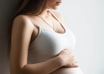 Adolescente embarazada con camiseta blanca mirando su vientre