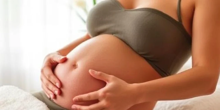 Mujer embarazada en posición de meditación tocando su vientre mientras se prepara para un masaje prenatal.